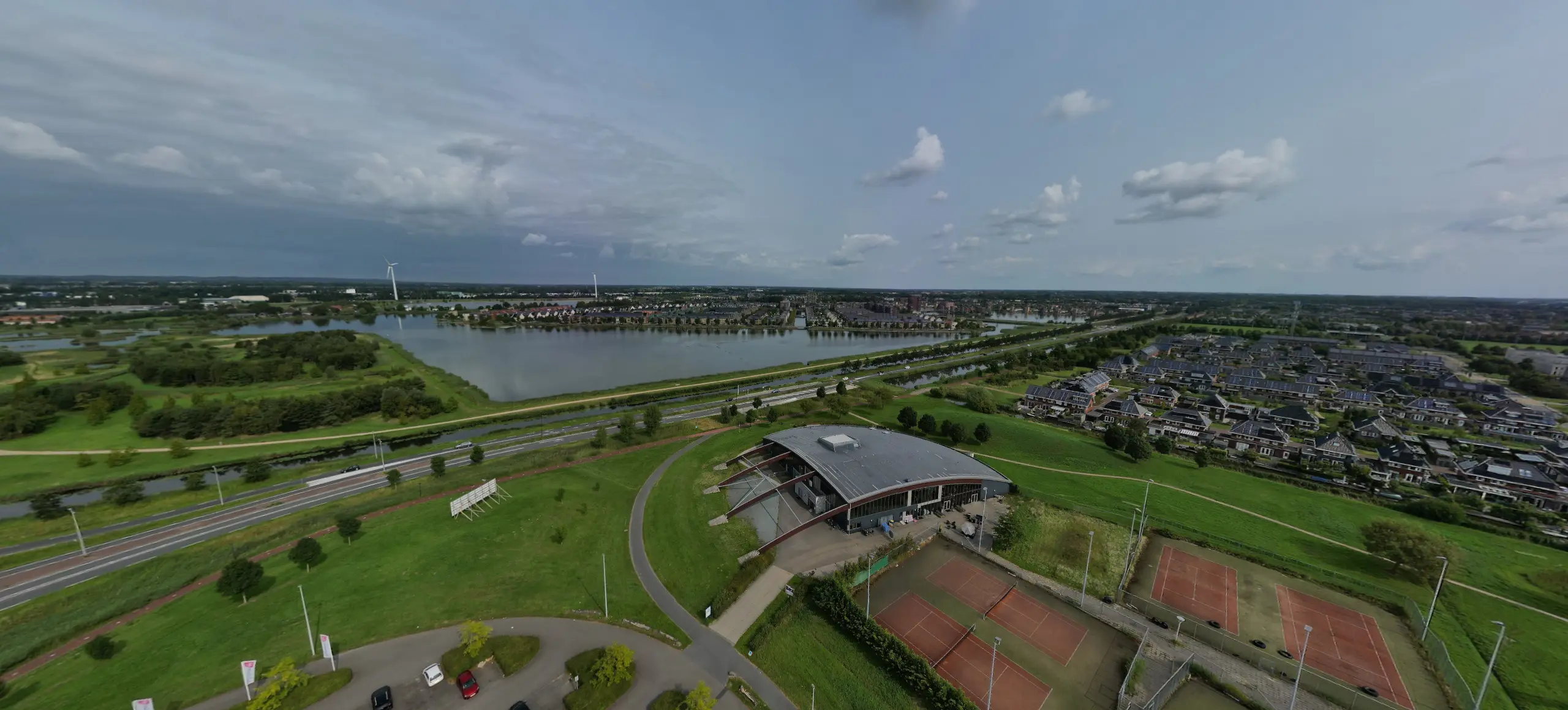 Beeld uit de voorbeeldtour: Heerhugowaard vanuit de lucht, met het kanaal, de sporthal en de tennisbanen.